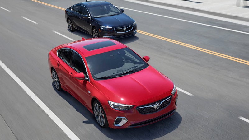 A red and black Buick Regal driving next to each other