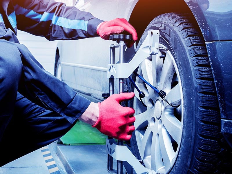 car mechanic preforming a tire alignment on a car
