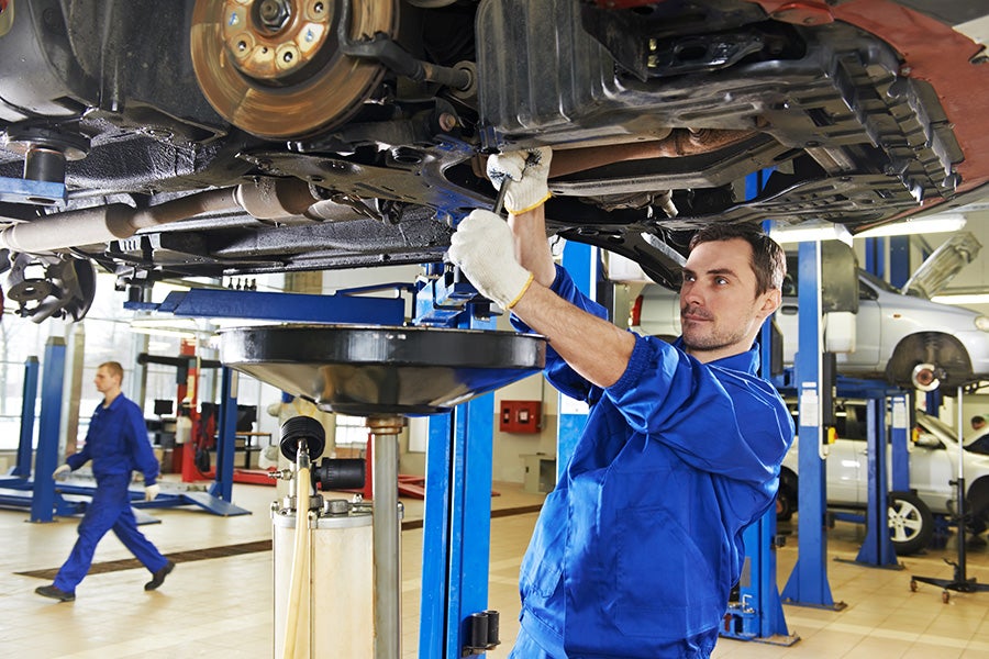 service technician performing oil change on lifted truck